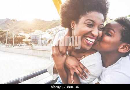 Happy young mother having fun with her child in sunny day - Son kissing his mum outdoor with back sun light - Family lifestyle, motherhood, love and t Stock Photo