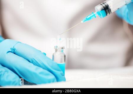 Doctor hands in blue gloves holding syringe and vaccine injection. Medicine concept. Stock Photo