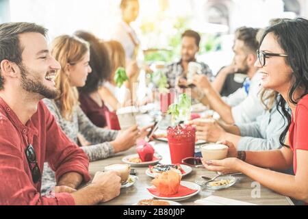 Happy friends having coffee break at bar cafeteria - Students enjoying breakfast together - Friendship and good mood concept - Focus on right woman - Stock Photo