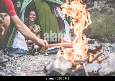 Hikers couple camping in rock mountains with their dog - People relaxing after a climbing day making fire next to the tent - Travel, nature life and v Stock Photo