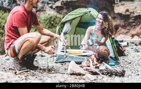 Trekkers couple cooking dinner in rock mountains - Hikers having fun in excursion weekend vacation - Travel, nature lifestyle, love and holiday concep Stock Photo