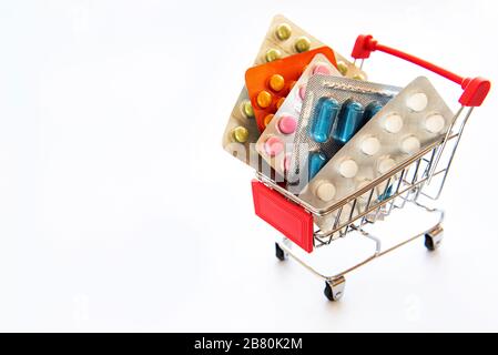 Miniature shopping cart filled with pills, tablets and capsules: pharmacy shopping, medicine and drug abuse concept. Coronavirus concept. Stock Photo