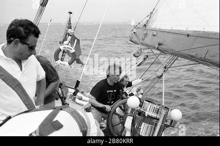 Helmsman putting in a shift on board the J Class yacht 'Velsheda' (K7): sailing in the Solent after first refit, summer 1991.  Archive black and white film photograph Stock Photo