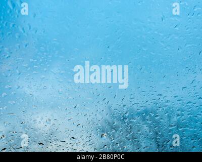 Wet window with rain drops and a cloudy sky outside background. Stock Photo