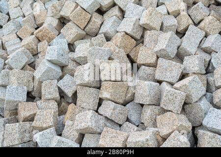 Stone paving stones, for laying the road, poured into a pile for construction work. Close-up Stock Photo