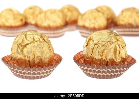 Group chocolate candies wrapped in gold. On a white background. Stock Photo