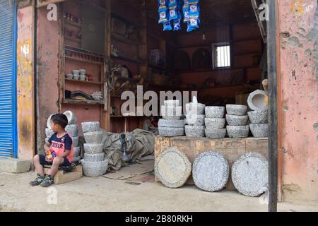 A  child sitting in a stone workshop in Kashmir under lockdown. Stock Photo