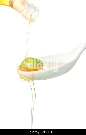 In a porcelain spoon of olive oil poured from a bottle. Stock Photo