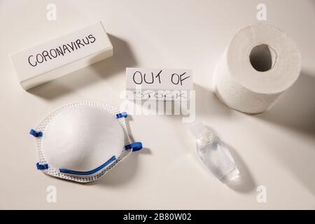 Coronavirus essentials out of stock concept,shortage personal masks, hand sanitizer and toilet paper, coronavirus text on white flay lay, top view Stock Photo