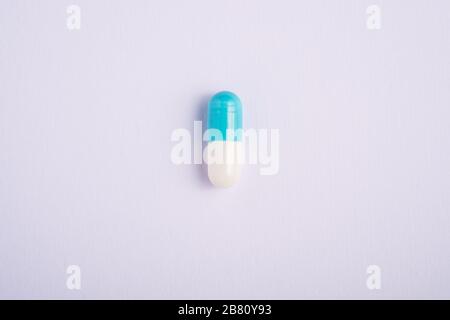 Single blue pill on bright white background, healthcare medical concept, antibiotics and cure, top view copy space Stock Photo