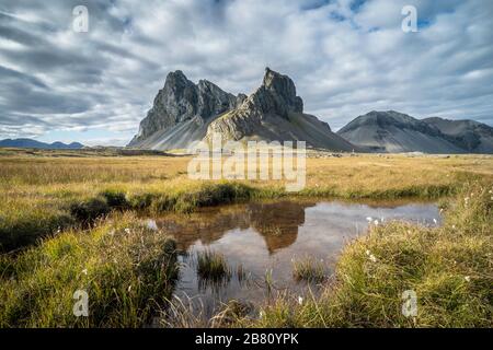 Eystrahorn mountain in south eastern Iceland in autumnal evening sunlight mirroring in a little lake, Landscape photography