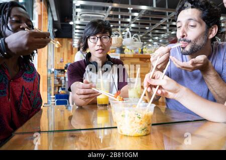 Multiethnic group eating Asian food together in a modern restaurant Stock Photo