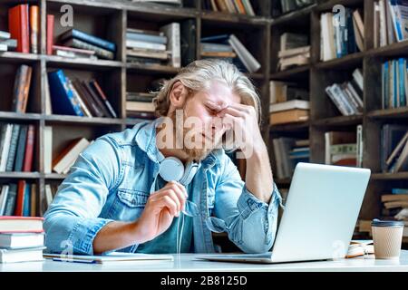 Young stressed tired man take off glasses rub closed eyes have vision problems. Stock Photo