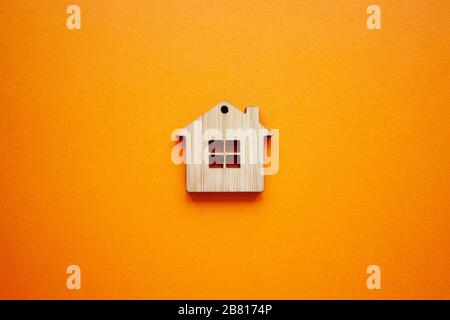 House, insurance and mortgage, buing and rent concept. Small wooden house toy on orange background top view Stock Photo
