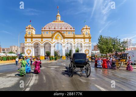 Entrance arch (Portada) and women wearing traditional flamenco dress at the April Fair ((Feria de Abril), Seville Fair Stock Photo