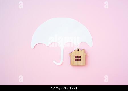 House insurance concept, house protection. Umbrella and wooden toy house for protect your house and property concept. Stock Photo