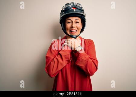 Middle age motorcyclist woman wearing motorcycle helmet over isolated white background shouting and suffocate because painful strangle. Health problem Stock Photo