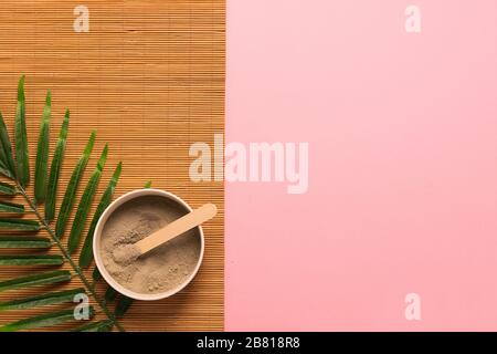 Natural skin care products at home. Gray clay in a jar brush sponge made of natural eco-friendly material on a pink background with green leaves. Hori Stock Photo