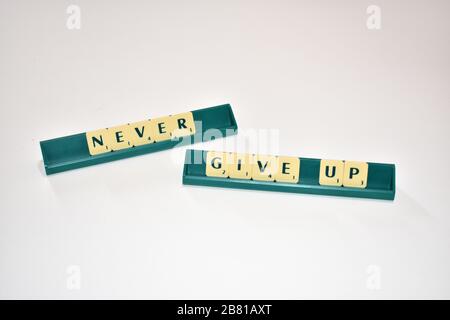 Scrabble tiles spell out Never Give up Motivational quote Scrabble Blocks Letters Grey Background Life quote Induce Alphabet. Stock Photo