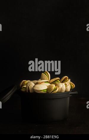 Green pistachios in a black bowl on a dark background Stock Photo