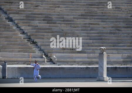 Athens, Greece. 19th Mar, 2020. Greek Olympic medalist in artistic gymnastics Eleftherios Petrounias holds the Tokyo Olympic Flame at the Panathenaic stadium, in Athens, Greece, on March 19, 2020. Credit: Aris Messinis-pool photo/Xinhua/Alamy Live News Stock Photo