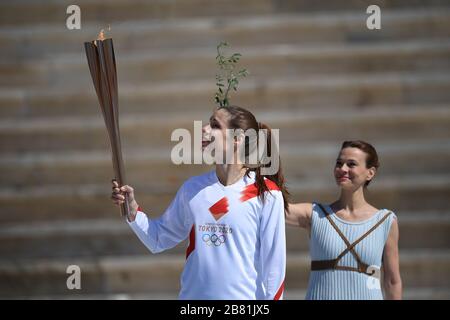 Athens, Greece. 19th Mar, 2020. Greek Olympic medalist in pole vault Katerina Stefanidi(L) holds the Tokyo Olympic Flame at the Panathenaic stadium, in Athens, Greece, on March 19, 2020. Credit: Aris Messinis-pool photo/Xinhua/Alamy Live News Stock Photo