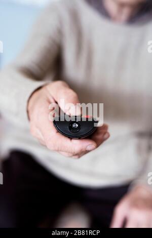 closeup of a senior old caucasian woman sitting in a couch using a remote control Stock Photo