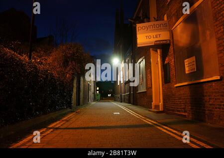 Old pub to let sign down an empty street in the town at night Stock Photo