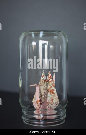 An origami crane trapped in a glass jar. Stock Photo