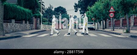 People in bacteriological protection suits walking down an empty street Stock Photo