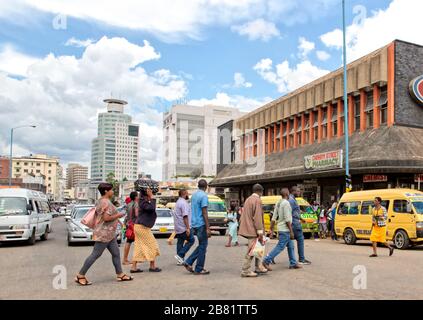 People walk in front of the traffic, across Jason Moyo Ave at its junction with Chinhoyi Street in Harare Stock Photo