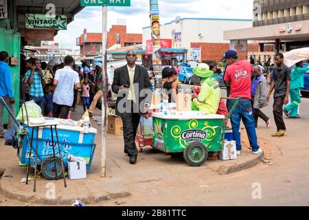Smartly dressed in suit and tie, the man looks out of place as he walks up Albion Street to Chinhoyi, through the groups of people and street vendors Stock Photo