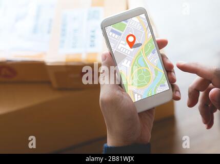 Delivery and online shopping concepts with young person using digital map with smartphone on product package box.Ecommerce market.Transportation logis Stock Photo