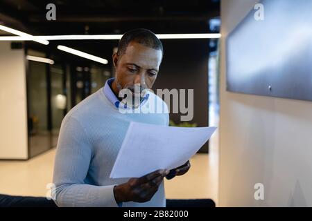 African American man reading papers in office Stock Photo