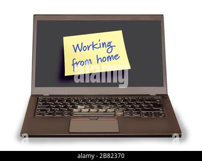 Notebook pc with a yellow sticky note saying Working from home on the empty screen. Computer isolated on white background. Stock Photo