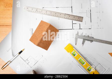 Business, architecture, building and construction concept - Top view of architects house model with measurement tool and blueprints on architect desk Stock Photo