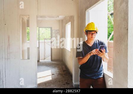 Engineer or Architect using cell phone in building construction site. Stock Photo