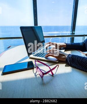 Woman using laptop computer, searching the web, browsing information while traveling on a ship