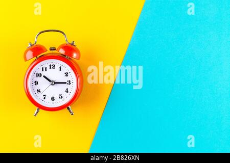 Red vintage alarm clock on a blue and yellow background. Alarm clock with place for text. Time management concept, business planning Stock Photo
