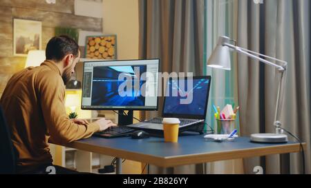 Back view of of young game developer in his home office working on graphics of the interface. Stock Photo