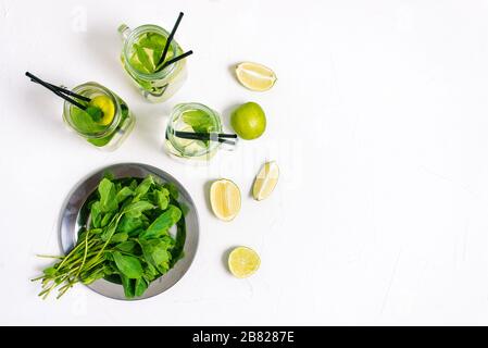 Cooking Mojito. Ingredients for an alcoholic drink on the table. Fresh mint, lime slices and glass cocktail jars. Top view, copy space. Stock Photo