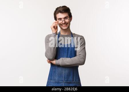 Portrait of friendly smiling guy working in coffee shop, fixing glasses on eyes and looking camera with enthusiastic positive expression, invite Stock Photo