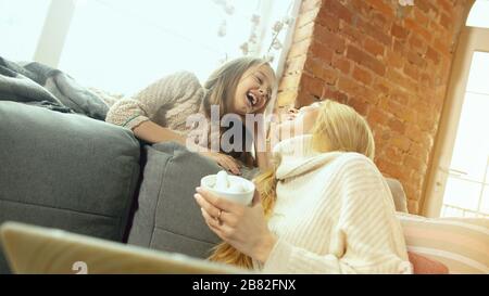 Girl's talks and secrets. Happy loving family. Mother and daughter spending time together at home. Watching cinema, using laptop, laughting. Mother's day, celebration, weekend, holiday childhood concept. Stock Photo