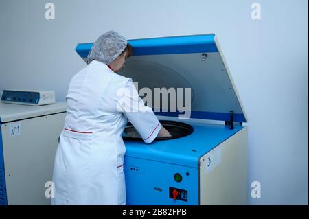 Nurse placing containers with blood in a centrifuge Stock Photo