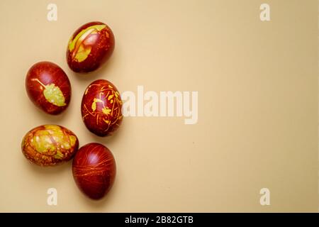 Chicken eggs colored with old-fashioned natural method by onion husks isolated on light brown. Topview of brown eggs with different natural patterns w Stock Photo
