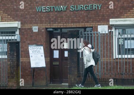 Cardiff, Wales, Uk. 19th Mar, 2020. CARDIFF, WALES, UNITED KINGDOM - MARCH 19, 2020 - A woman walks past a GP surgery in Cardiff with a large coronavirus sign warning people not to enter. Credit: Mark Hawkins/Alamy Live News Stock Photo