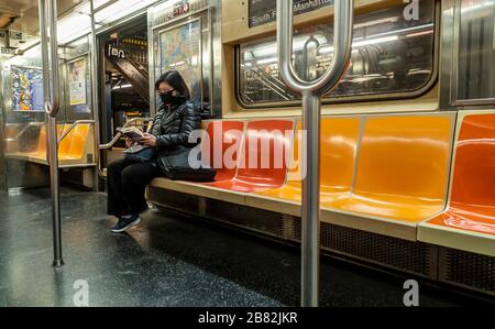 A woman wears a surgical mask in a nearly empty subway car  in New York on Wednesday, March 18, 2020. Subway ridership has dropped 60 percent due to the covid-19 pandemic and the MTA is seeking a $4 billion bailout. (© Richard B. Levine) Stock Photo