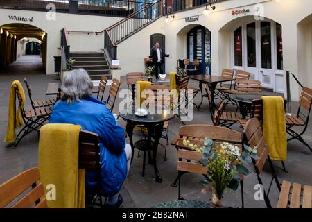 London, UK. 19 March 2020. A busker performs operatic songs to a lone customer at a cafe in Covent Garden. Stock Photo