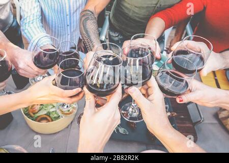 Happy family toasting with red wine glasses at dinner outdoor - People having fun cheering and drinking while dining together Stock Photo