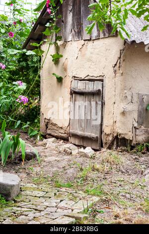 Old cob goat house with wooden door in a countryside garden Stock Photo